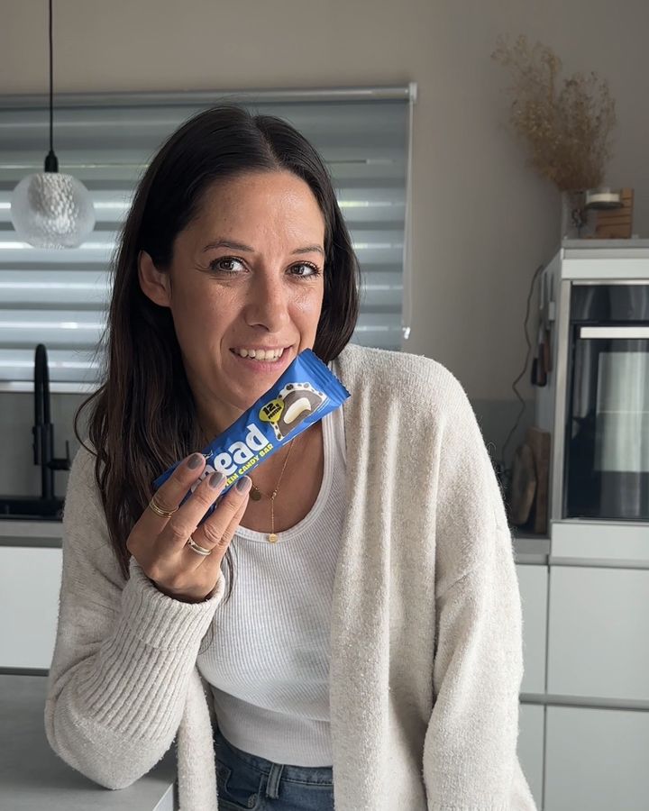 Angelique hält einen ahead Proteinriegel in der Küche